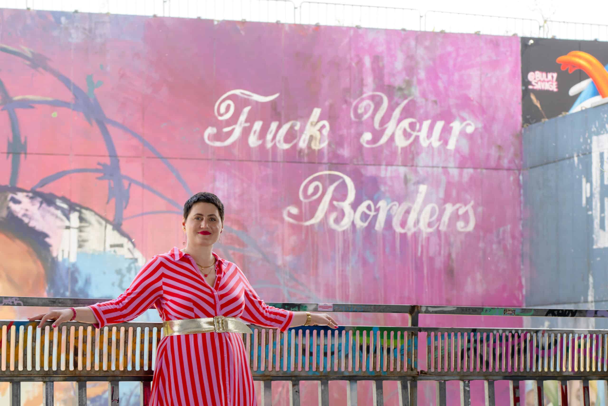Luisa Riffel – im Hintergrund die Botschaft „Fuck your borders“, die für innere Freiheit, Mut zur Veränderung und Selbstbestimmung steht.