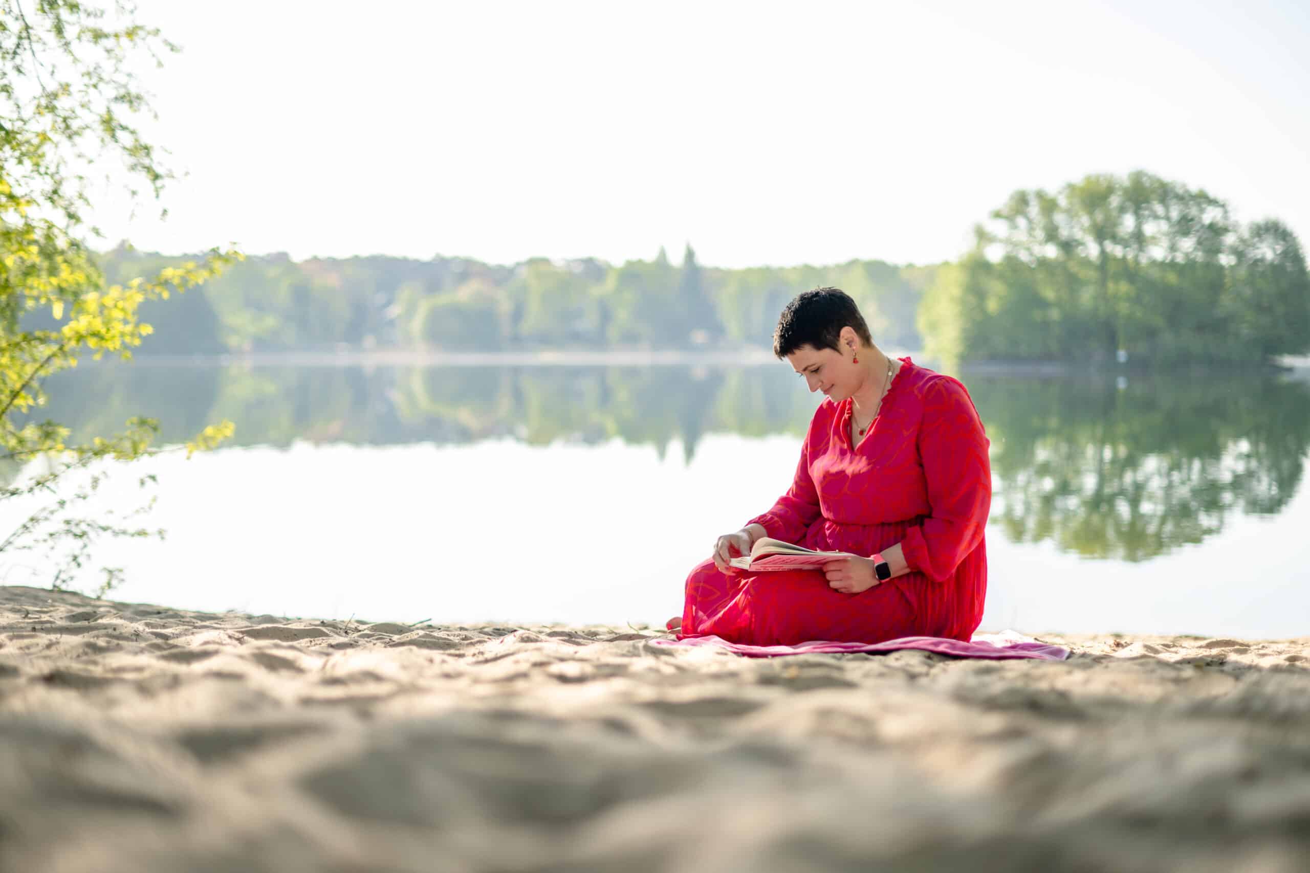 Luisa Riffel sitzt in einem ihrer Lieblingskleider am Glienicker See und liest ein gutes Buch über Female Empowerment